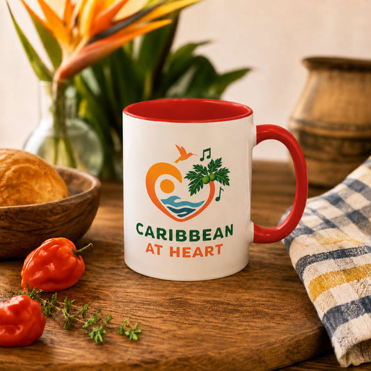 Caribbean At Heart logo accent mug with red handle and interior featuring heart, hummingbird, waves and breadfruit leaves.
