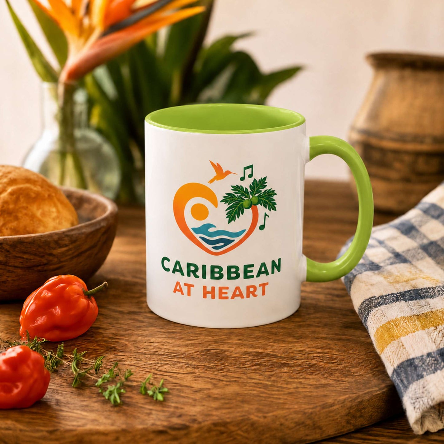 Caribbean At Heart logo accent mug with light green handle and interior featuring heart, hummingbird, waves and breadfruit leaves.