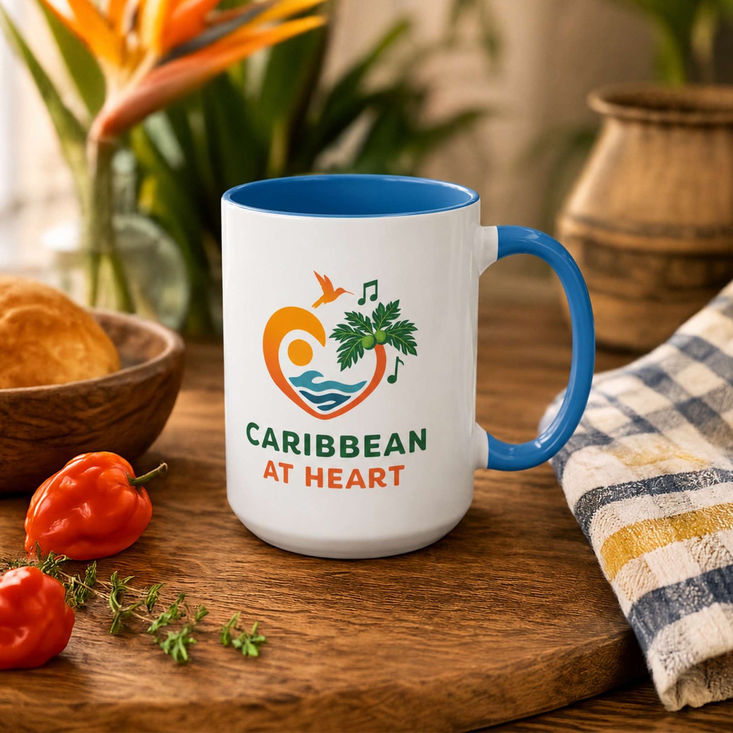 Caribbean At Heart logo accent mug with blue handle and interior featuring heart, hummingbird, waves and breadfruit leaves.