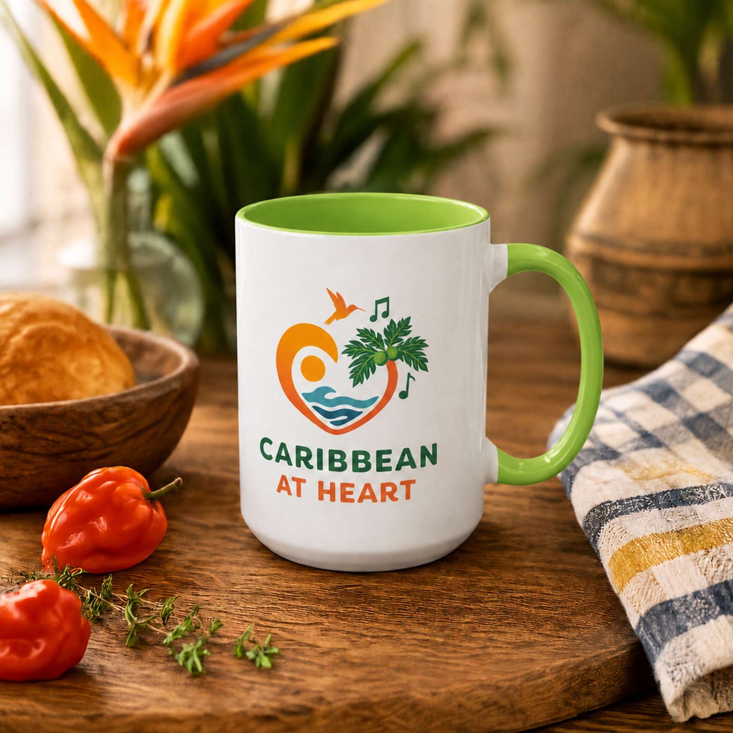 Caribbean At Heart logo accent mug with light green handle and interior featuring heart, hummingbird, waves and breadfruit leaves.