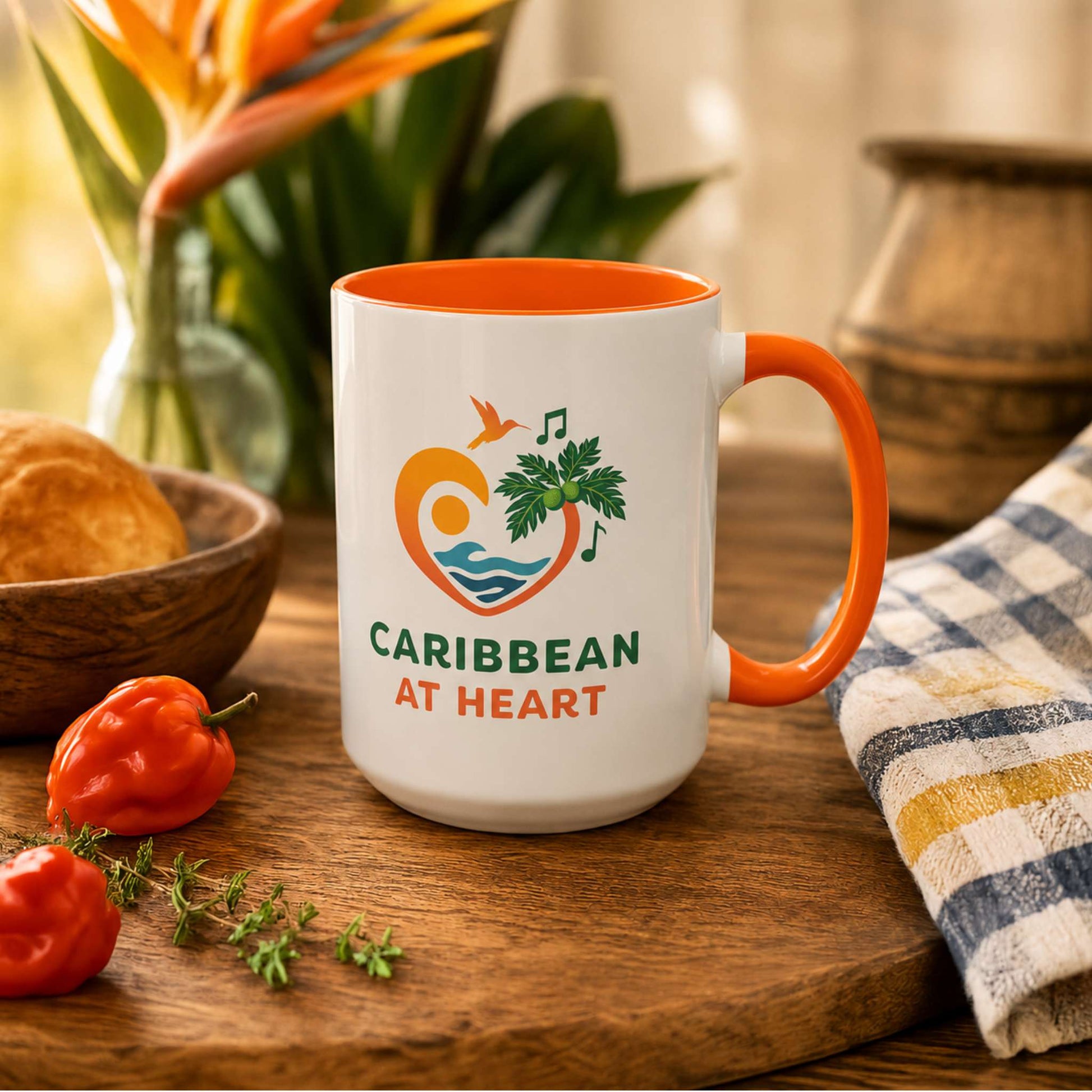 Caribbean At Heart logo accent mug with orange handle and interior featuring heart, hummingbird, waves and breadfruit leaves.