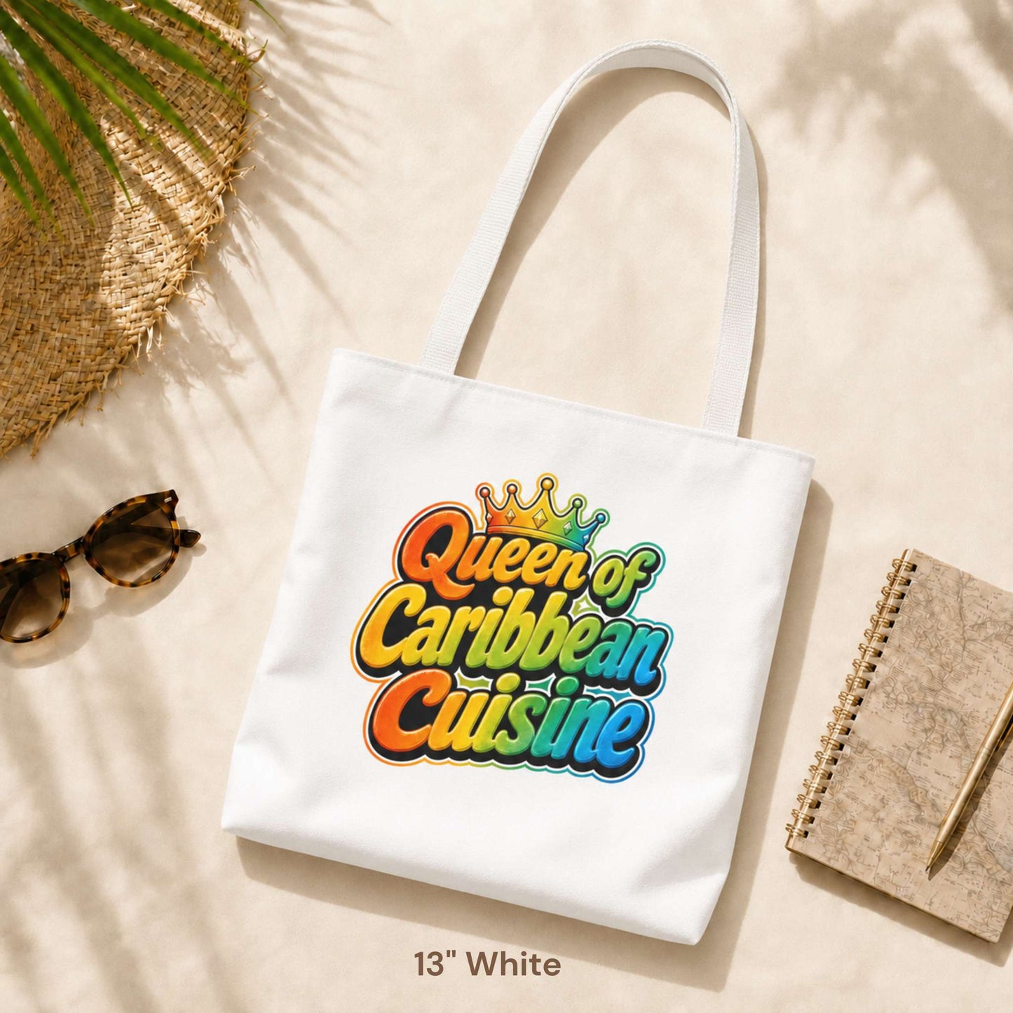 Queen of Caribbean Cuisine tote bag with colorful crown graphic and white shoulder handles, available in three sizes.